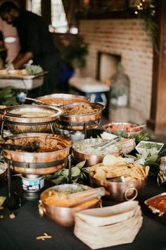 a table filled with lots of food on top of a black table covered in plates and bowls