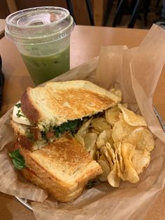 a sandwich and chips on a table next to a drink