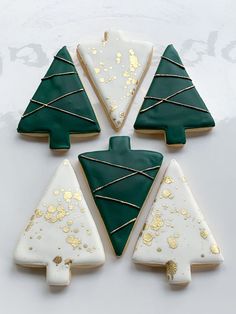 four decorated cookies with green and white icing in the shape of christmas trees on a table