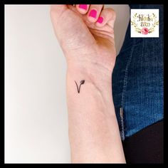 a woman's arm with a small black arrow tattoo on the left side of her wrist