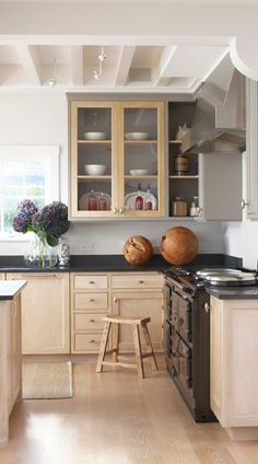 a kitchen with wooden cabinets and black counter tops, white walls and wood flooring