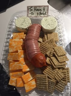 a hot dog, crackers and cheese on a plastic tray