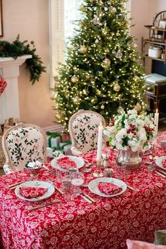 a christmas tree is in the background behind a table with plates and silverware on it