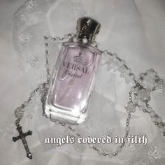 a bottle of perfume sitting on top of a white lace covered tablecloth next to a cross