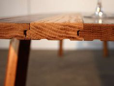 a wooden table with two wine glasses sitting on it's top and one glass in the background