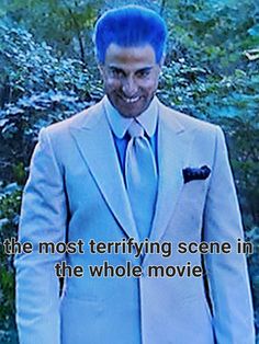 a man with blue hair wearing a white suit and tie in front of some trees