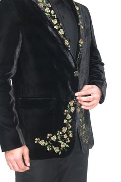 a man in a black suit with flowers on the lapel and one button down