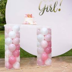 a table topped with pink and white balloons next to a sign that says, it's a girl