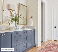 a bathroom with blue cabinets and gold accents on the countertop, along with an area rug