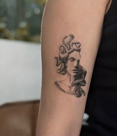 a woman's arm with a tattoo on it that has a snake crawling around her head