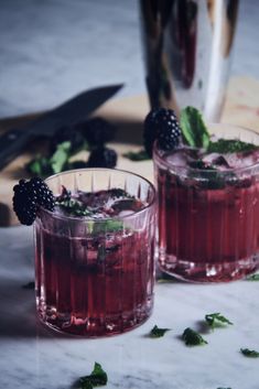 two glasses filled with raspberry mojitas and mint garnishes