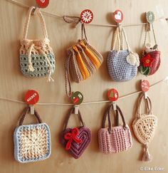 crocheted purses hanging on a clothes line with tags attached to the strings