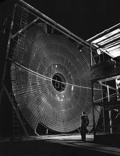 a man is standing in front of a large object that looks like a giant wheel