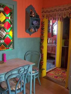 a dining room table and chairs in front of a stained glass window with colorful accents