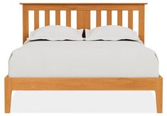 a wooden bed frame with two pillows on top of it, and one side is turned down