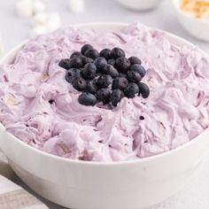 a white bowl filled with blueberries and whipped cream