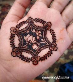 a hand holding a henna tattoo on it's left palm, with flowers and leaves in the center