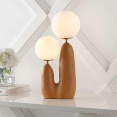 two wooden lamps sitting on top of a white table next to a vase with flowers