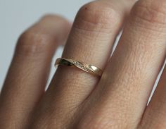 a woman's hand with a gold wedding ring on top of her left hand