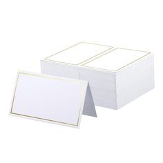 two white cards with gold trims are stacked next to each other on a white surface