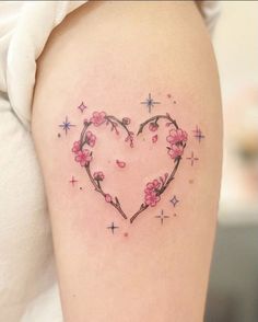 a heart shaped tattoo with pink flowers and stars on the side of her thigh,