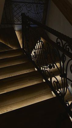 the stairs are made of wood and wrought iron with light coming from them on either side