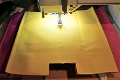 the sewing machine is working on the yellow piece of fabric that has been sewn