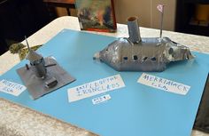 two metal boats sitting on top of a blue tablecloth covered table with white writing