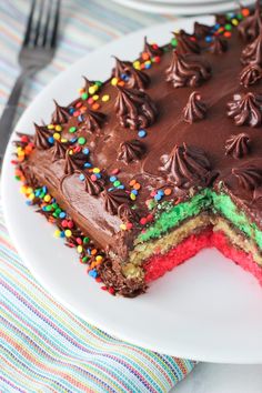 a cake with chocolate frosting and sprinkles on a plate next to a fork