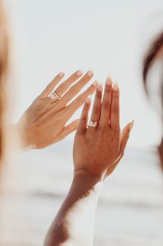 two hands reaching out towards each other with the ocean in the background