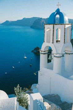 a white church with blue domes overlooking the ocean