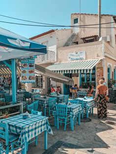 people are sitting at tables in an outdoor dining area with blue and white checkered tablecloths