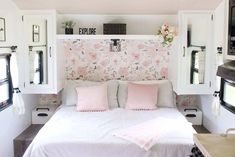 a white bed sitting inside of a bedroom next to two windows