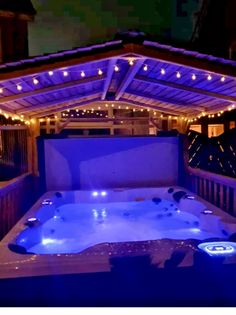 an outdoor hot tub lit up at night with christmas lights on the roof and above it