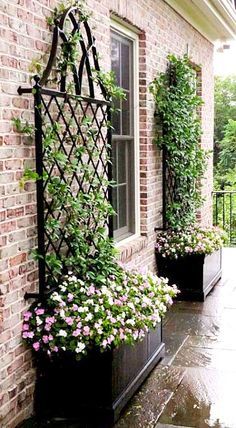 two black planters filled with flowers next to a brick building on a rainy day