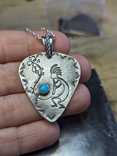 Sterling silver guitar pick pendant with Kokopelli and small genuine turquoise stone charm necklace .  Pick is of course handmade and playable . 1.3 inch by 1.2 inch with a thickness of 1mm  backside with hammered texture , my makers mark and a small STERLING stamp  The turquoise is from Kingman Arizona and is 5mm in size  Rustic patina and finish comes with an 18 inch sterling silver chain Artisan Adjustable Turquoise Necklace Nickel Free, Hippie Sterling Silver Nickel-free Jewelry, Nickel-free Sterling Silver Hippie Jewelry, Hippie Style Sterling Silver Nickel-free Jewelry, Adjustable Turquoise Pendant Necklace Nickel Free, Adjustable Nickel-free Turquoise Necklace With Round Pendant, Stamped Sterling Silver Turquoise Necklace For Gift, Stamped Sterling Silver Turquoise Necklace As Gift, Adjustable Nickel-free Turquoise Pendant Necklace