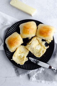 biscuits and butter on a black plate with a knife next to it, ready to be eaten