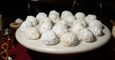 a white plate topped with snowball cookies on top of a red cloth covered table