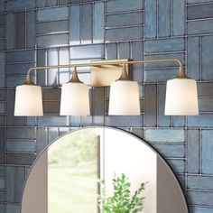 a bathroom with a round mirror and blue tile on the wall behind it is a vanity light