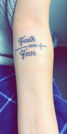 a person with a tattoo on their arm that says faith over fear in cursive writing