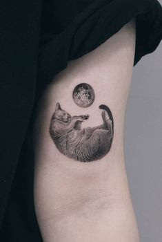 a cat and moon tattoo on the left side of the arm