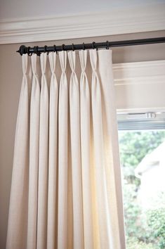 an open window with white curtains hanging from it's side and the curtain rod in front