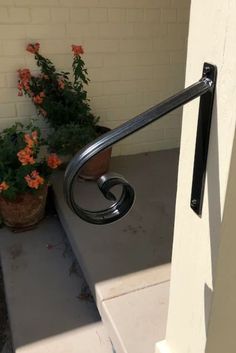 a metal handrail on the side of a building next to potted plants and flowers