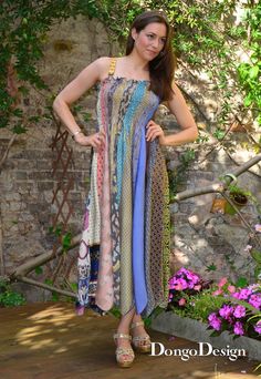 a woman standing in front of some flowers wearing a dress with an open back and multicolored print