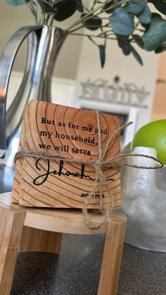 a piece of wood sitting on top of a wooden stool next to a vase filled with green apples