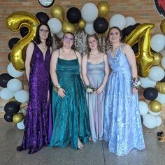 three women standing next to each other in front of balloons and number twenty five sign