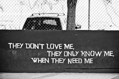 a black and white photo with words written on the wall next to a fence that reads they don't love me, they only know me, when they need me