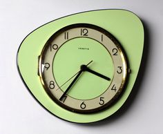 a green clock with black hands on a white surface