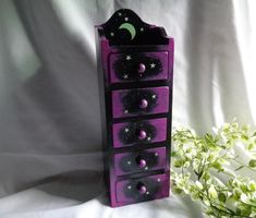 a purple drawer with stars and moon painted on it, next to a flower vase