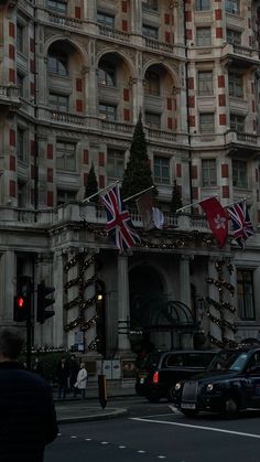 a very tall building with lots of flags on it's sides and cars parked in front